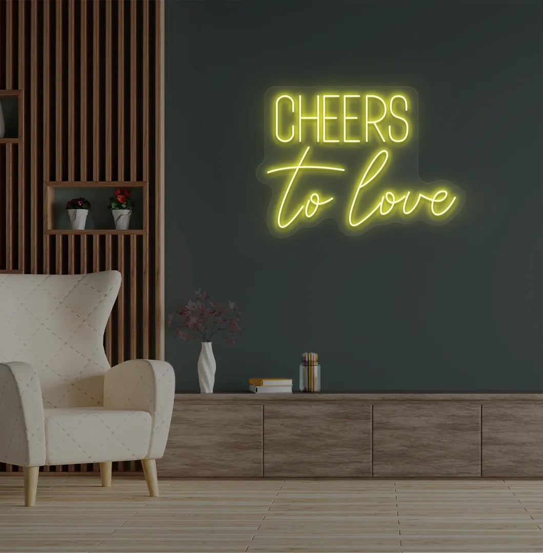 Image of a Romantic Cheers to Love yellow neon sign glowing on decorative wall.