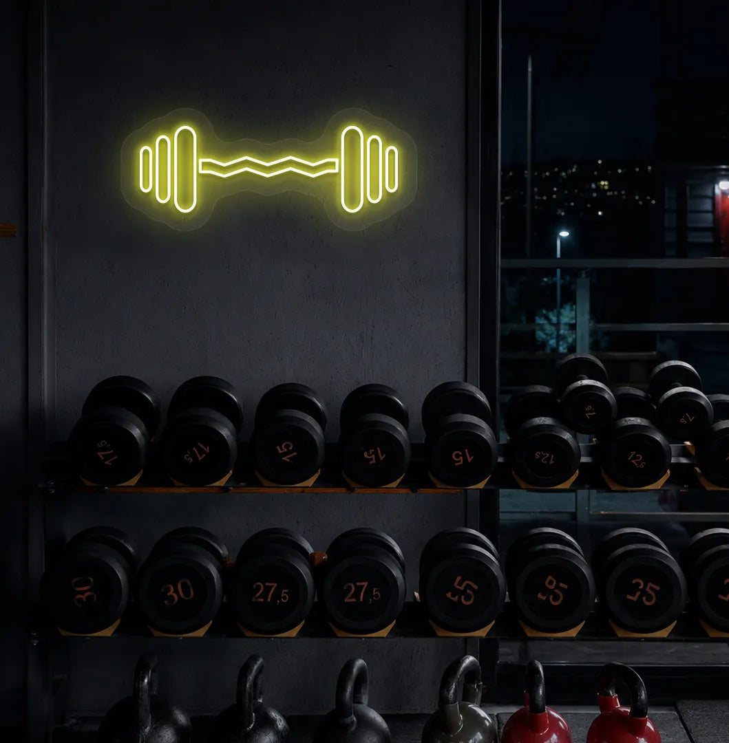 Trendy dumbbell neon sign in yellow mounted on fitness wall.