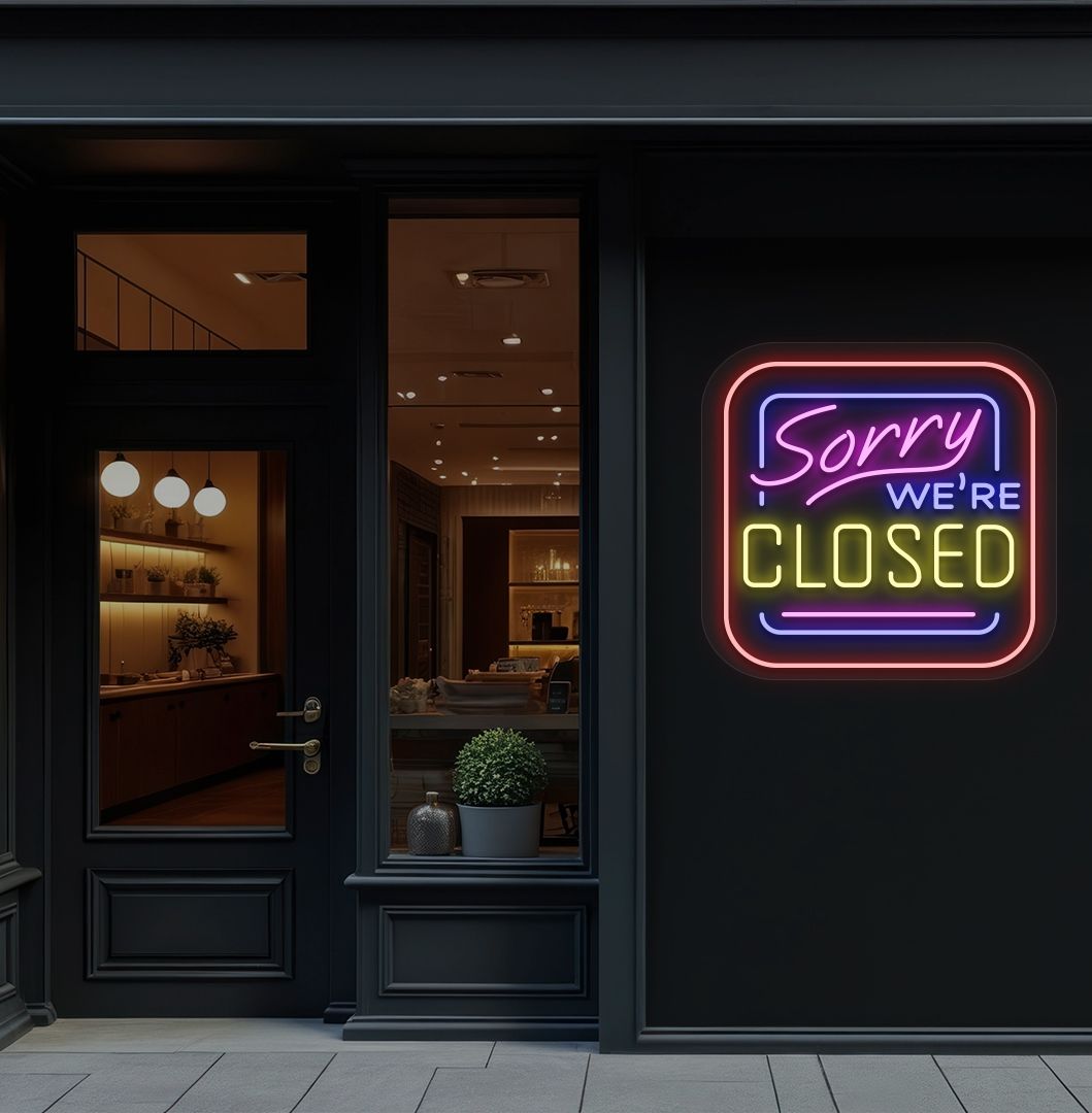 Storefront wall with sorry we're closed neon sign glowing yellow.