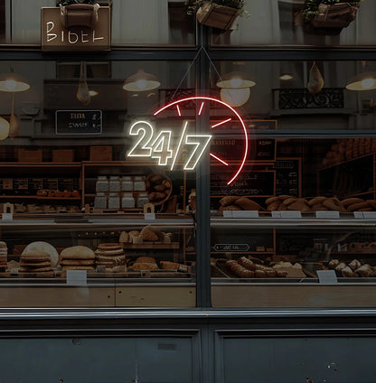 Warm white LED 24/7 clock neon sign glowing on bakery glass storefront.