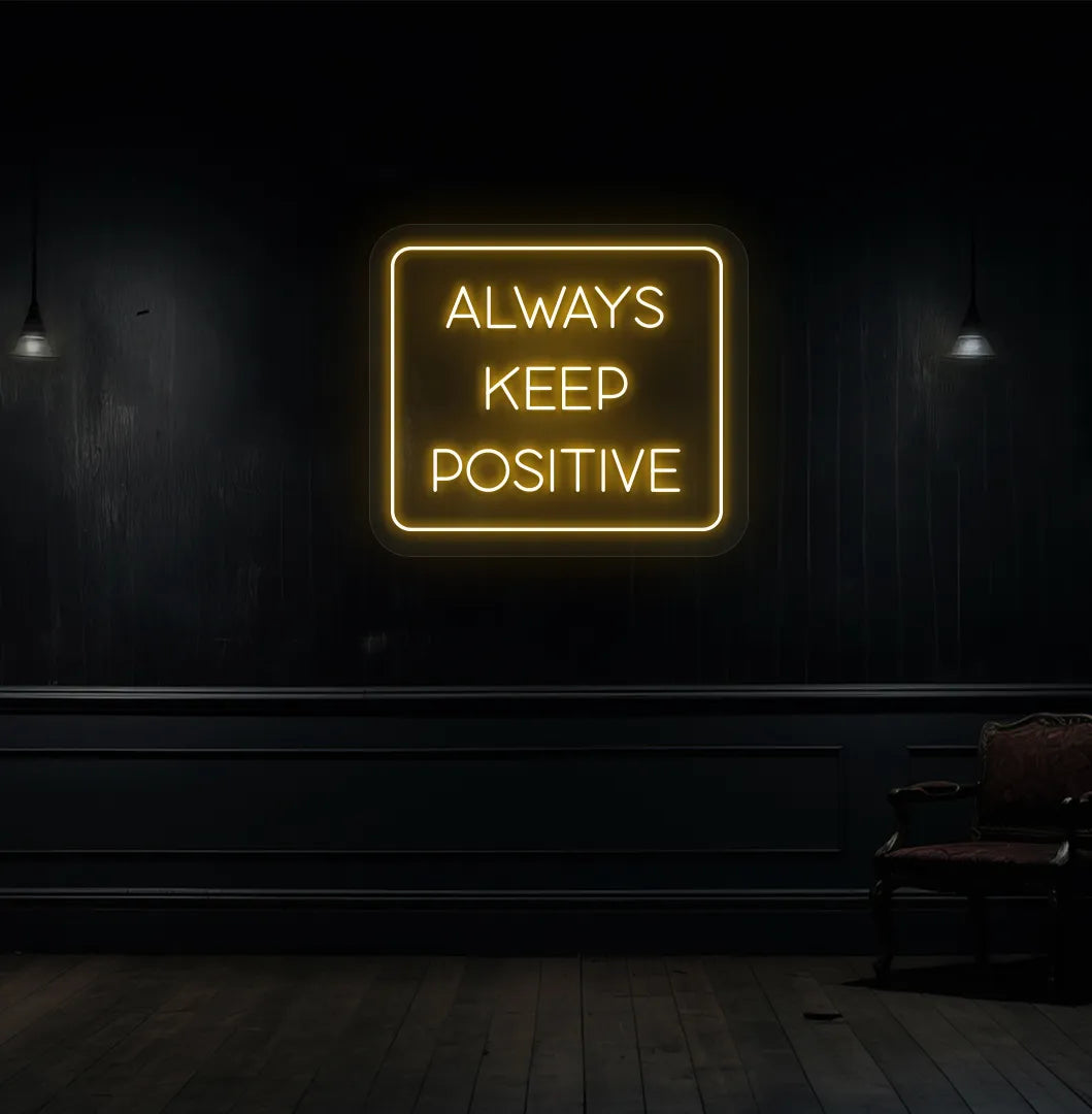 Modern aesthetic wall with "always keep positive" neon sign glowing orange.