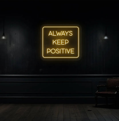 Modern aesthetic wall with "always keep positive" neon sign glowing orange.