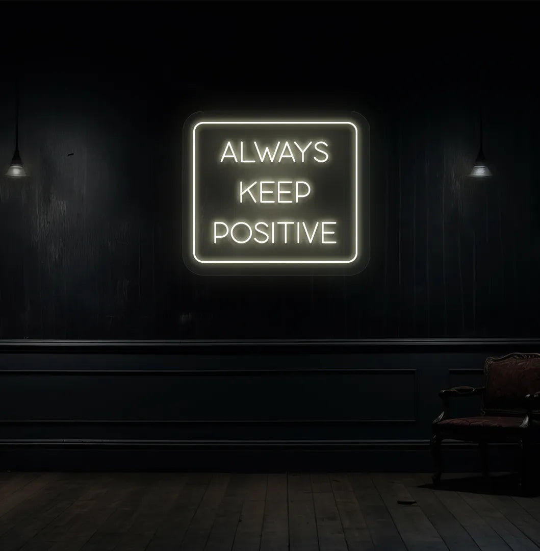 Modern aesthetic wall with "always keep positive" neon sign glowing warm white.