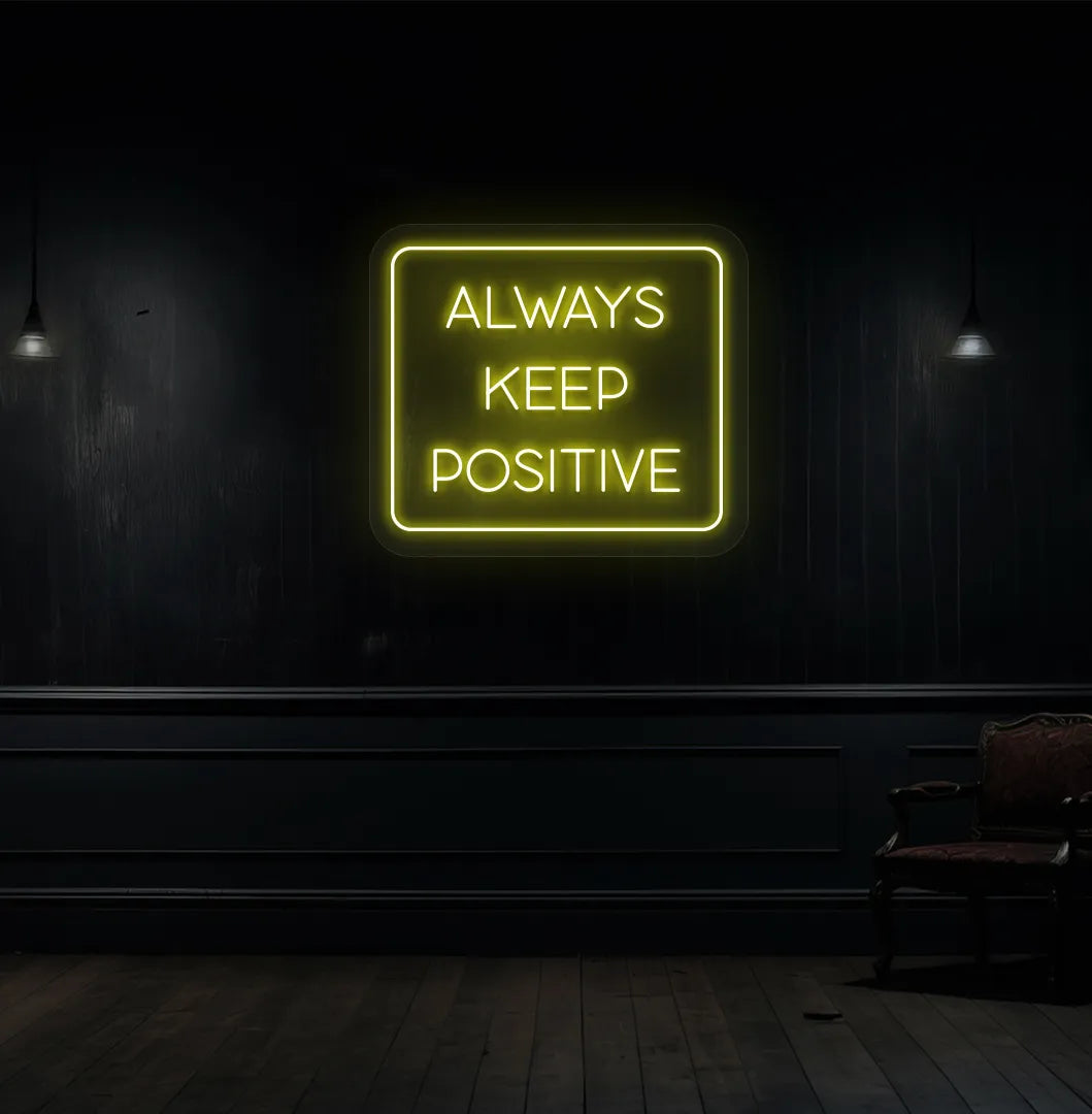 Modern aesthetic wall with "always keep positive" neon sign glowing yellow.