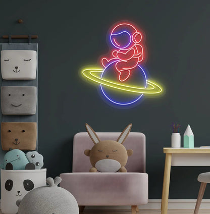Stylish astronaut sitting on planet neon sign mounted on children's wall in red color.