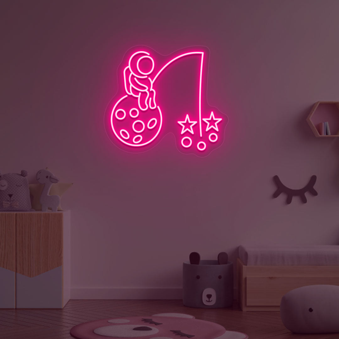 A creative pink LED astronaut neon sign catching stars glowing on a kid's room wall. Perfect for playrooms, space-themed interiors, and bedroom wall décor.