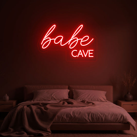 Image of a babe cave neon sign glowing on a bedroom wall in red color.