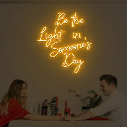 Image of an inspirational LED neon sign, "Be the light in someone's day," mounted on a wall in orange color.