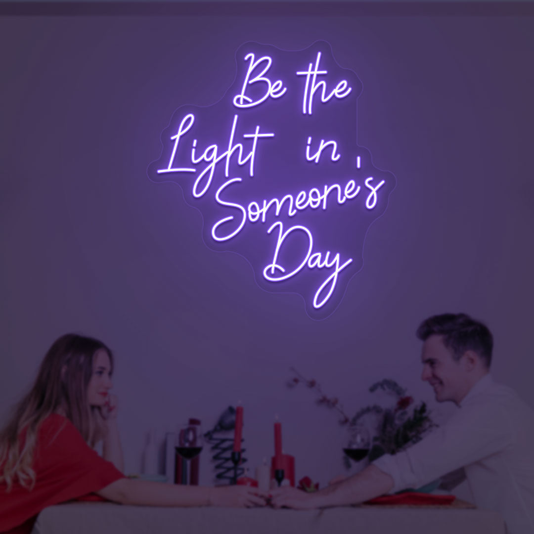 Aesthetic wall with "Be the light in someone's day" purple neon sign. 