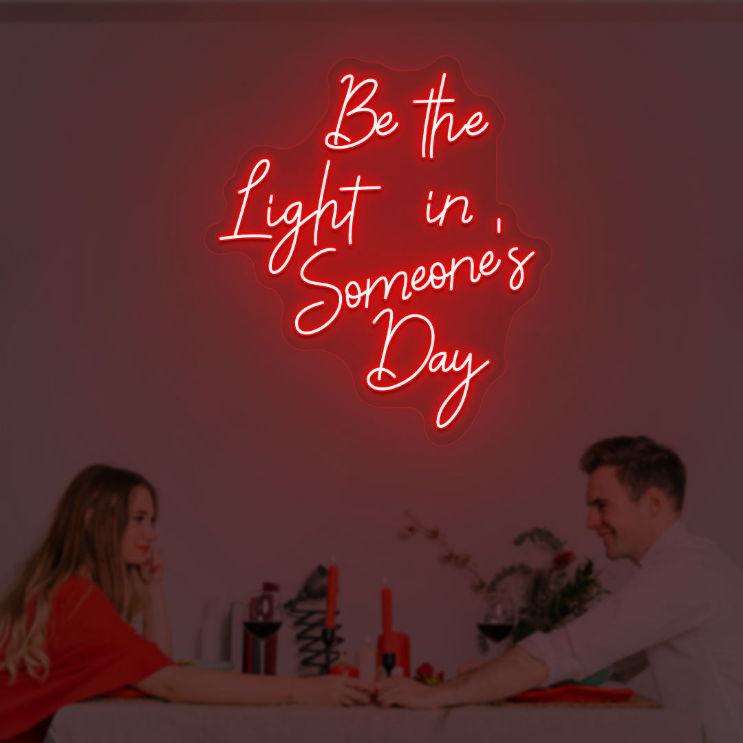 A soft red LED "Be the light in someone's day" neon sign is glowing on the wall.