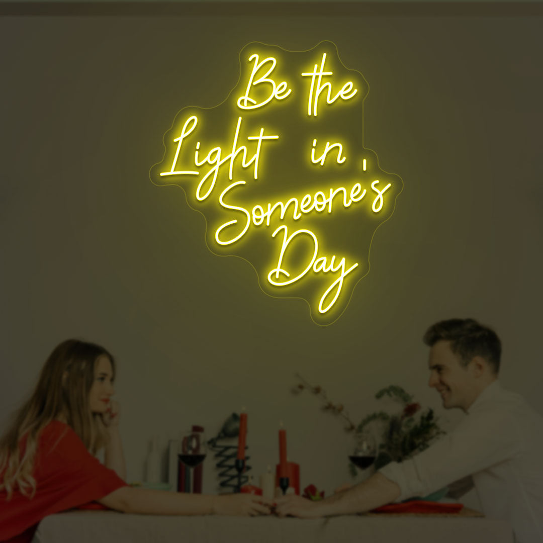 Image of an inspirational LED neon sign "be the light in someone's day" mounted on a wall in yellow color.