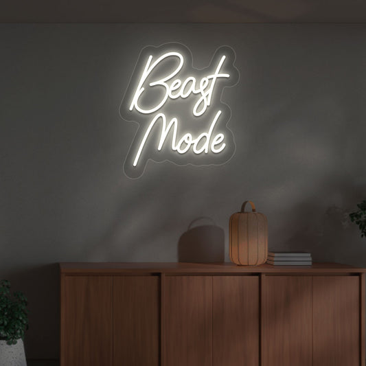 Image of a motivational "beast mode" neon sign mounted on a wall in warm white color.