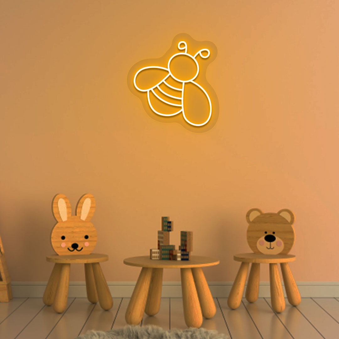 Image of a bee LED neon sign glowing on a kid's room wall in orange color.