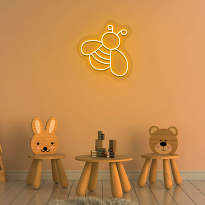 Image of a bee LED neon sign glowing on a kid's room wall in orange color.