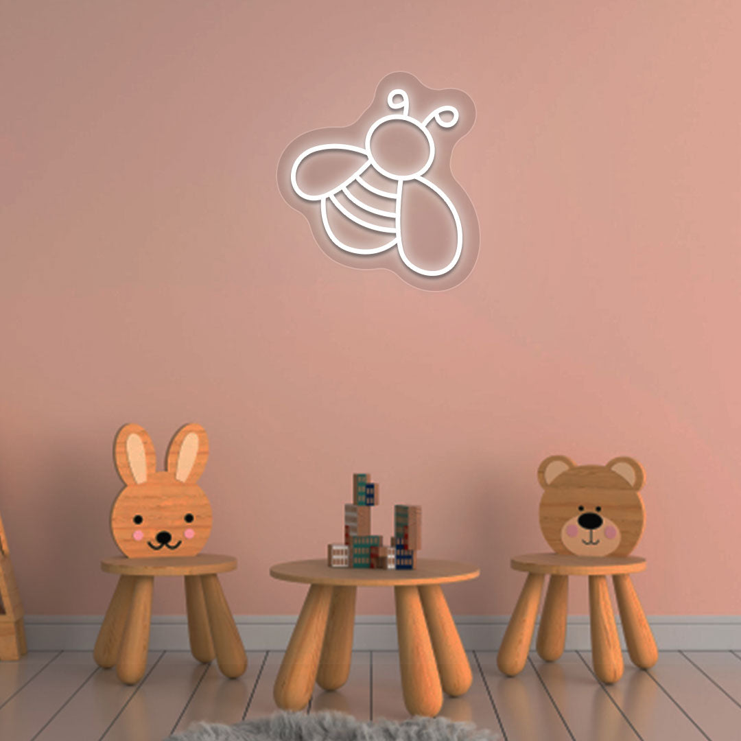 Image of a bee LED neon sign glowing on a kid's room wall in white color.