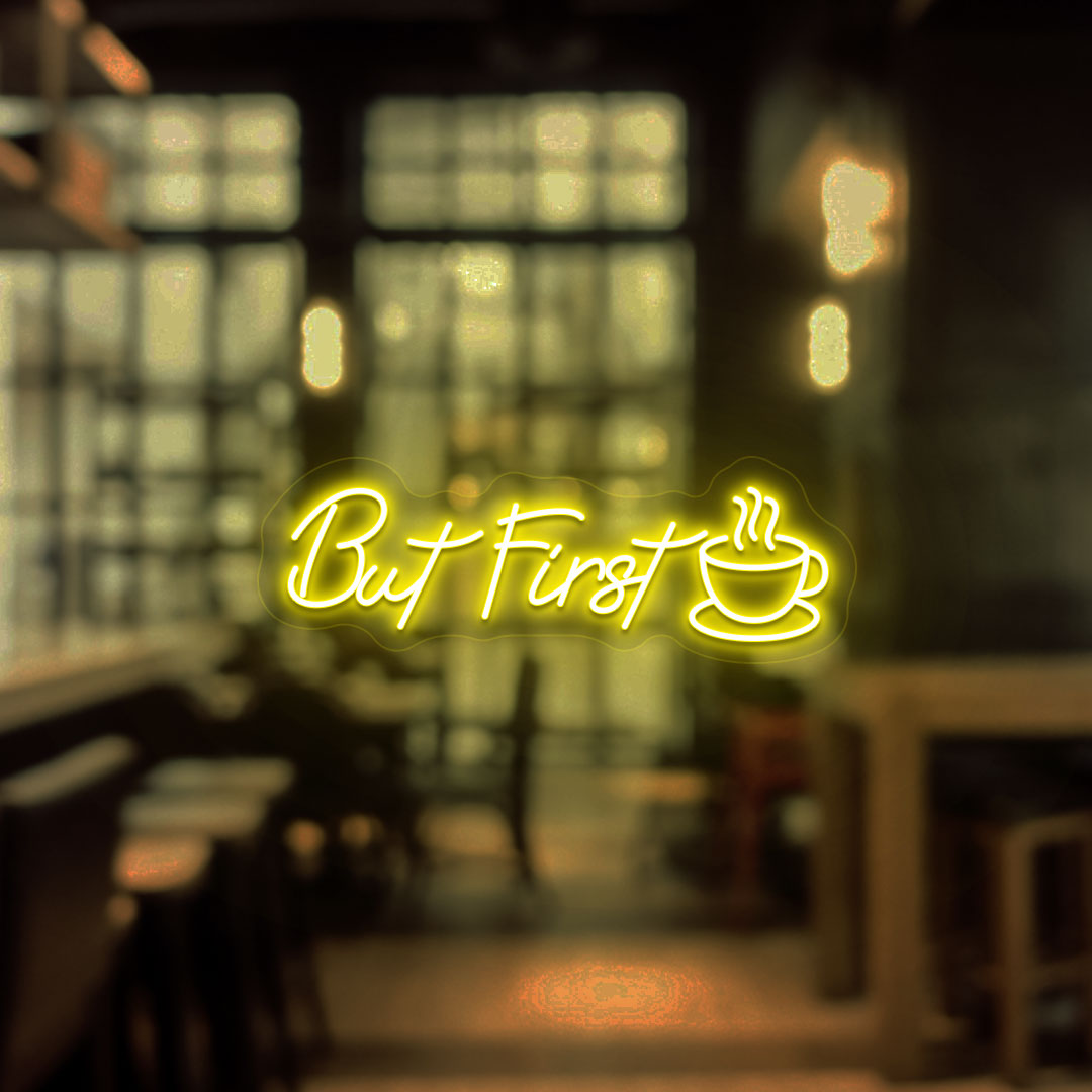 Image of a "but first" neon sign with a cup icon on a cafe entrance door in yellow color.