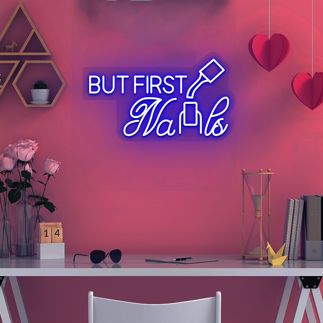 Image of a "but first nails" LED neon sign mounted on a salon wall in blue color.