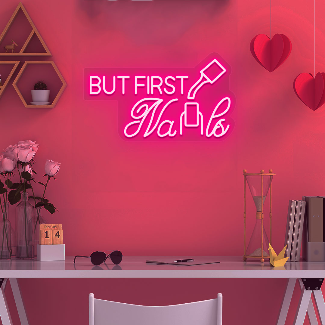 Image of a "but first nails" LED neon sign mounted on a salon wall in pink color.
