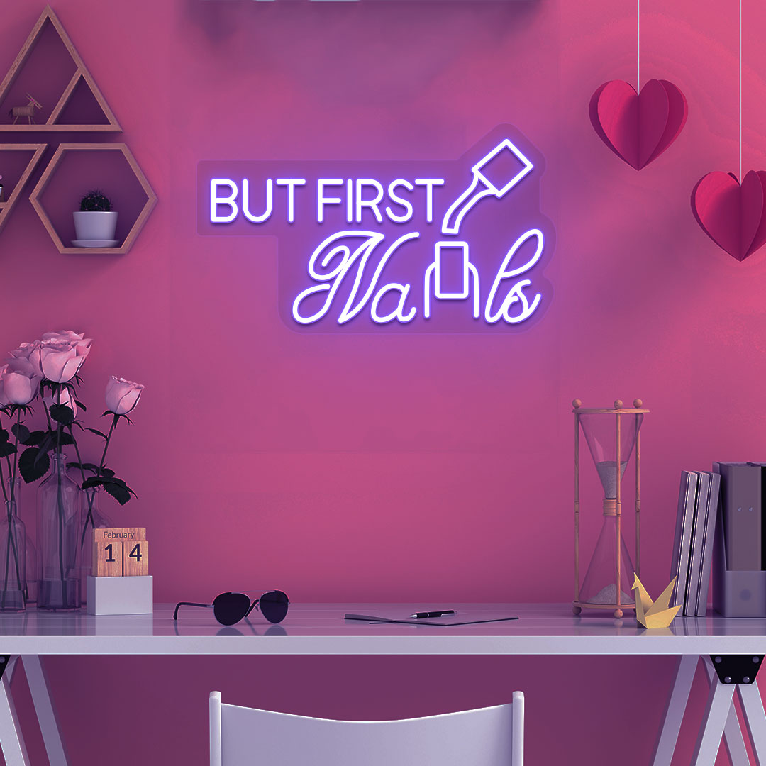 Beauty studio decor with purple LED "but first nails" neon sign glowing on the wall.