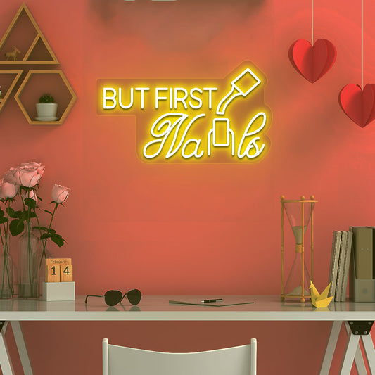 Image of a "but first nails" LED neon sign mounted on a salon wall in yellow color.