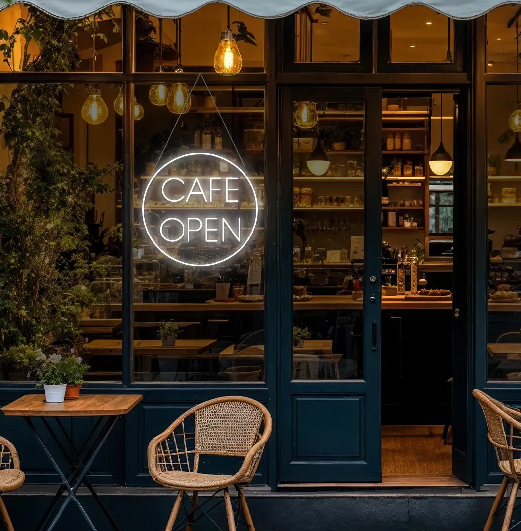 Image of a stylish cafe open in circle neon sign in white mounted on cafe wall.
