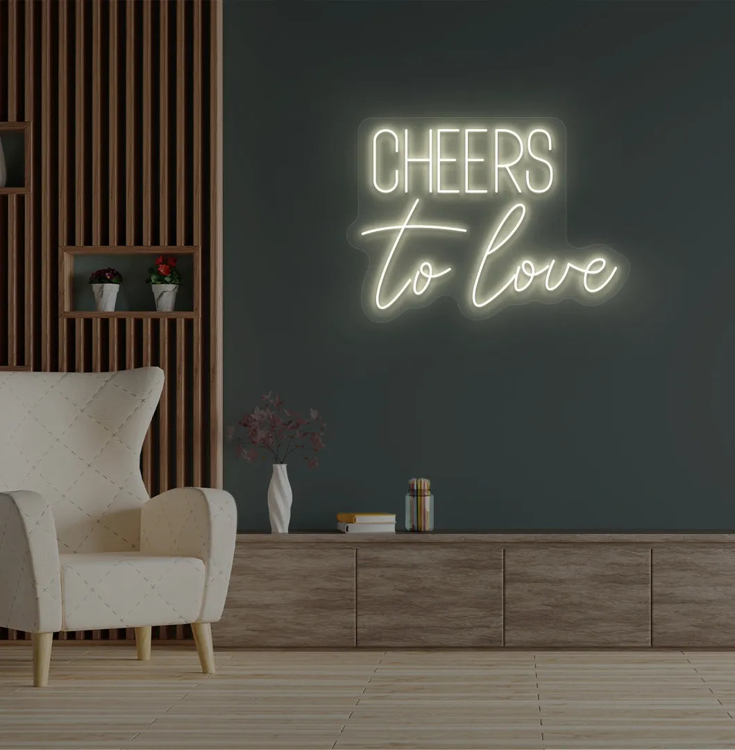 Image of a Romantic Cheers to Love warm white neon sign glowing on decorative wall.