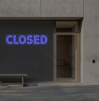 Image of a closed bold neon sign glowing on a shop exterior wall in blue.