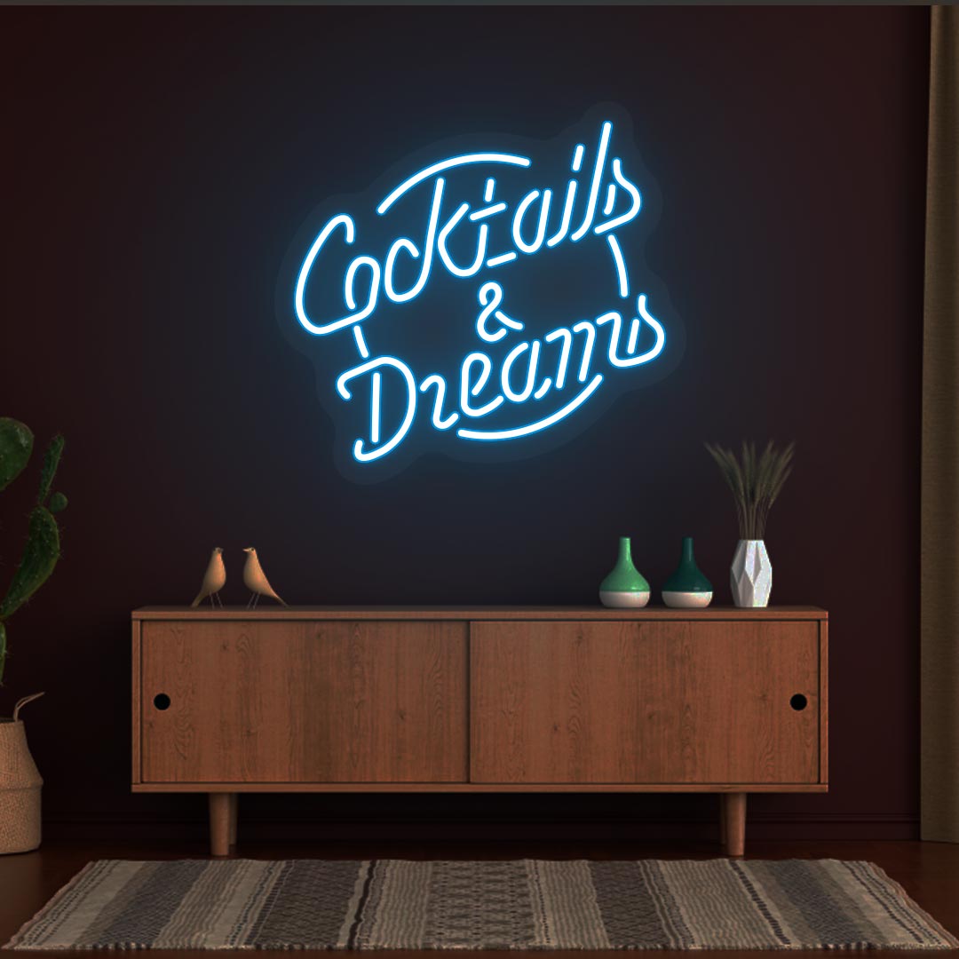 Image of a cocktail and dreams neon sign mounted on a bar wall in ice blue color.