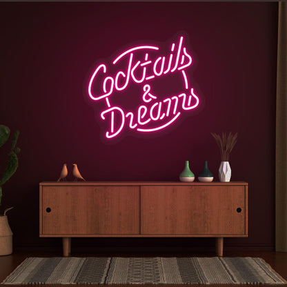 Decorative cocktail and dreams LED neon sign glowing pink on the wall.