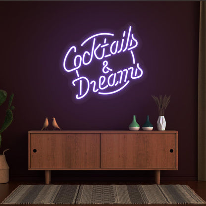 Decorative cocktail and dreams LED neon sign glowing purple on the wall.