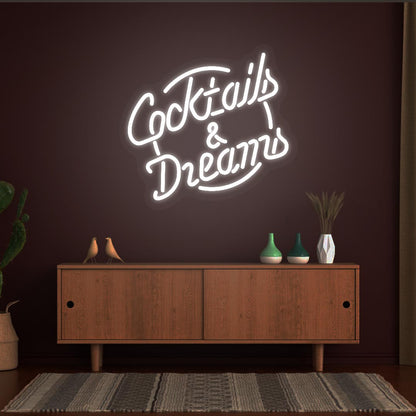 Image of a cocktail and dreams neon sign mounted on a bar wall in white color.