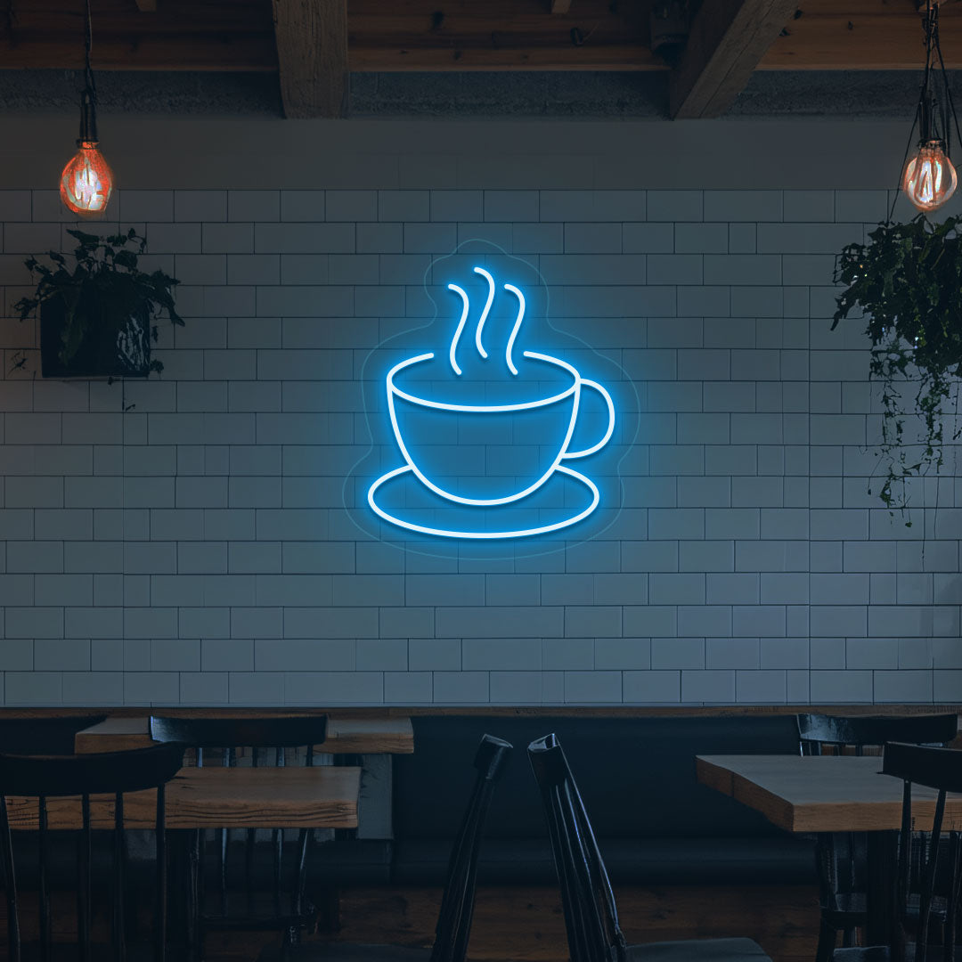 A bright ice blue LED coffee mug neon sign is mounted on the cafe wall. Perfect for coffee shops, bakeries, home coffee corners, and restaurants.