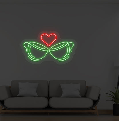 A cup heart LED neon sign in green color with two cups and a heart design mounted on a wall.