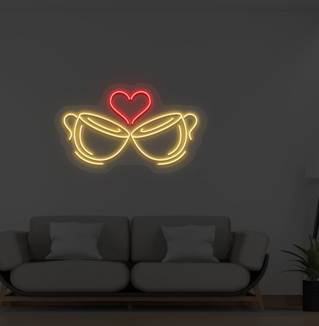 A cup heart LED neon sign in orange color with two cups and a heart design mounted on a wall.
