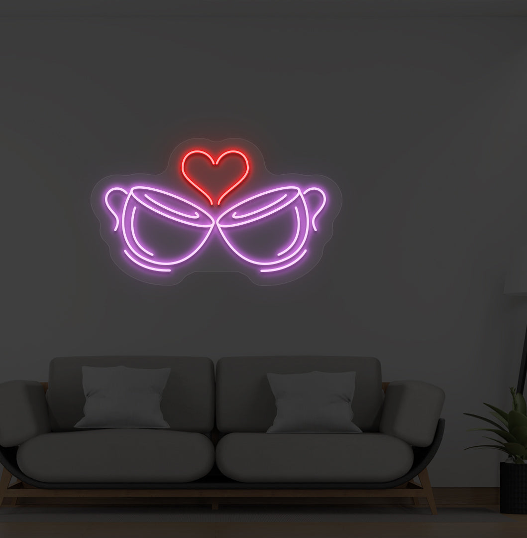 A cup heart LED neon sign in purple color with two cups and a heart design mounted on a wall.