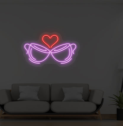 A cup heart LED neon sign in purple color with two cups and a heart design mounted on a wall.