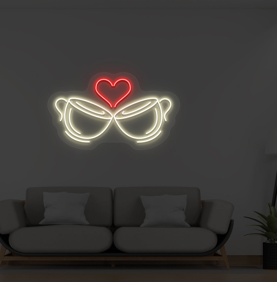 A cup heart LED neon sign in warm white color with two cups and a heart design mounted on a wall.