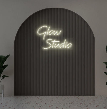Stylish personalized business name neon sign mounted on aesthetic wall in warm white color.