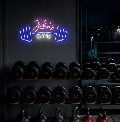 Custom GYM Name with Dumbbell LED neon sign mounted on modern fitness studio wall in purple color.