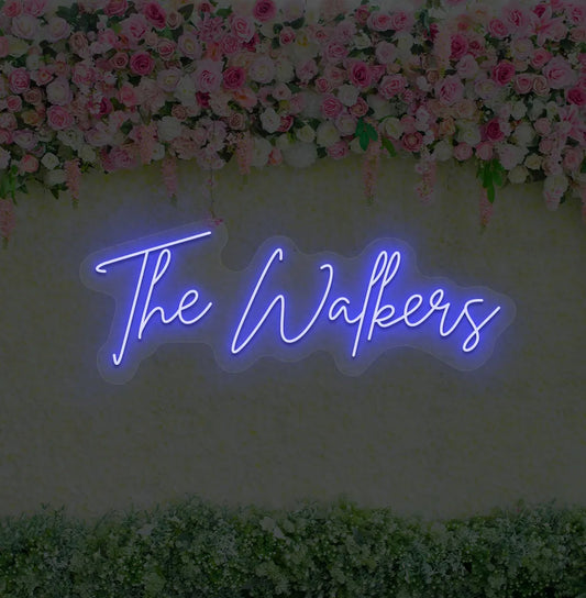 Personalized wedding neon sign glowing blue on wedding backdrop.
