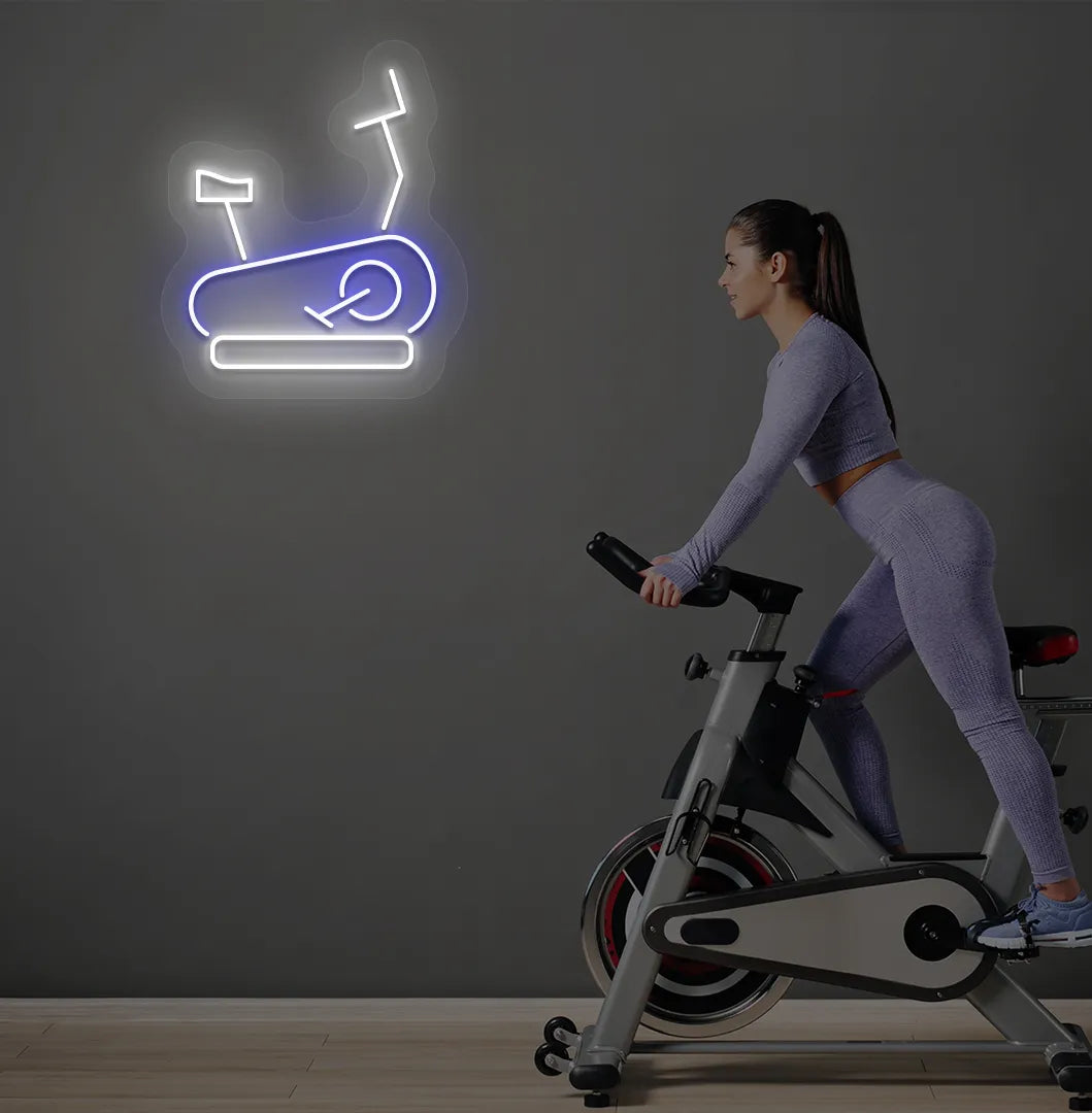 Image of a stylish "exercise cycle" neon sign mounted on gym wall in blue color.