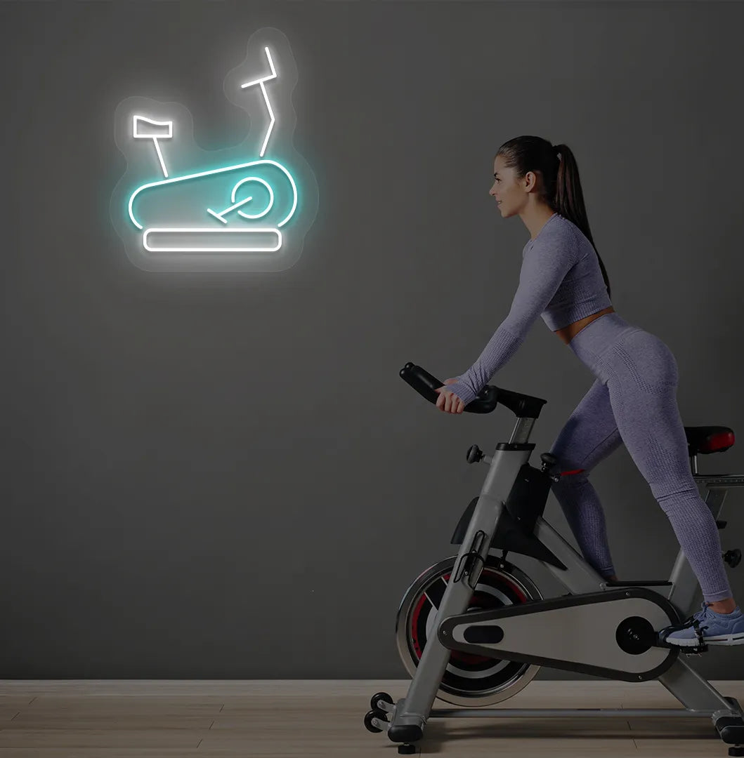 Image of a stylish "exercise cycle" neon sign mounted on gym wall in ice blue color.