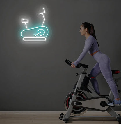 Image of a stylish "exercise cycle" neon sign mounted on gym wall in ice blue color.