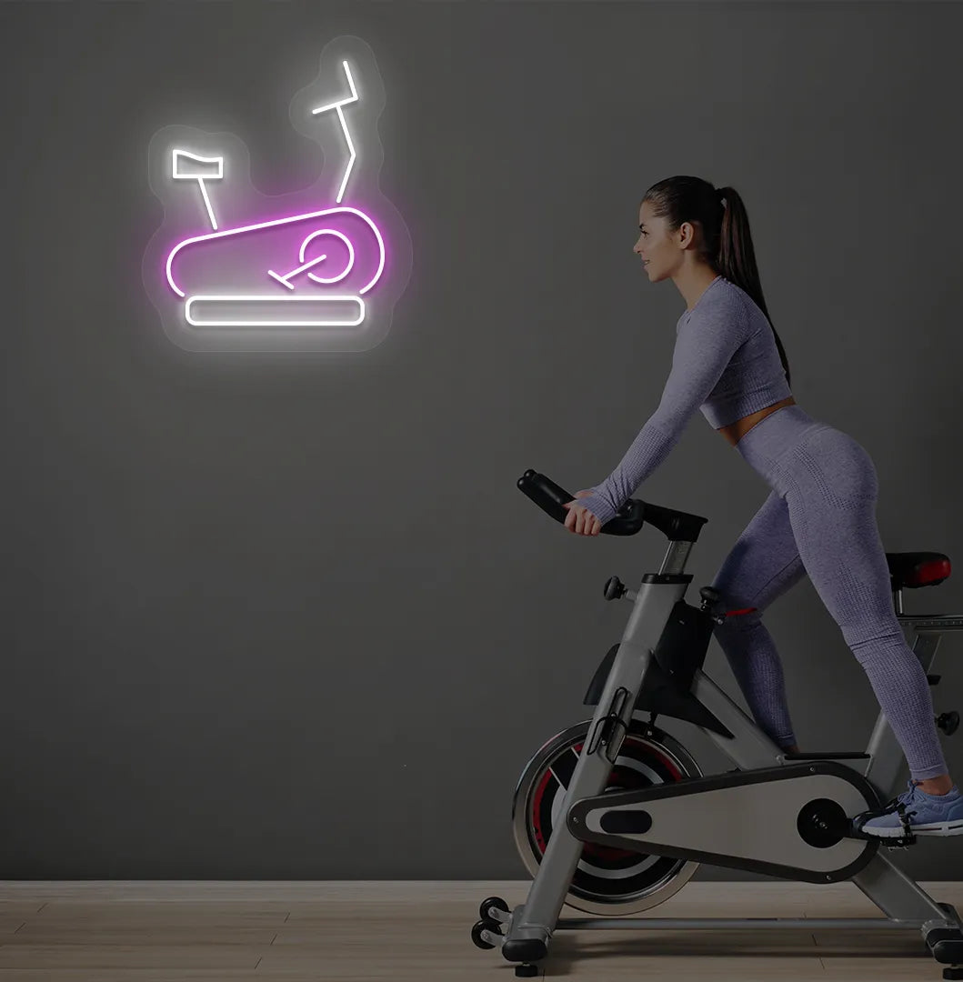 Image of a stylish "exercise cycle" neon sign mounted on gym wall in pink color.