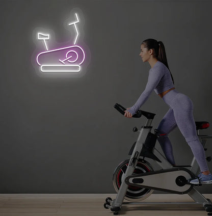 Trendy exercise cycle neon sign in purple mounted on fitness wall.