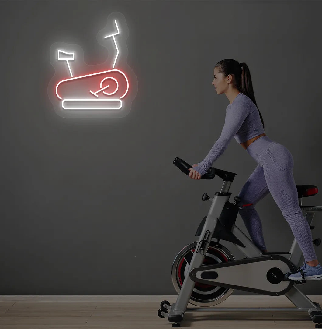 Image of a stylish "exercise cycle" neon sign mounted on gym wall in red color.