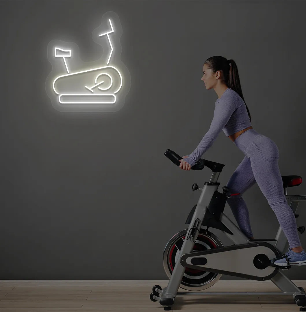 Trendy exercise cycle neon sign in warm white mounted on fitness wall.