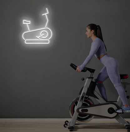 Image of a stylish "exercise cycle" neon sign mounted on gym wall in white color.