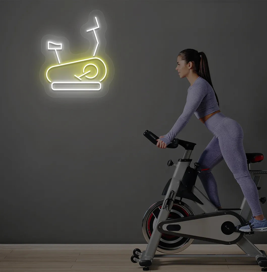 Trendy exercise cycle neon sign in yellow mounted on fitness wall.