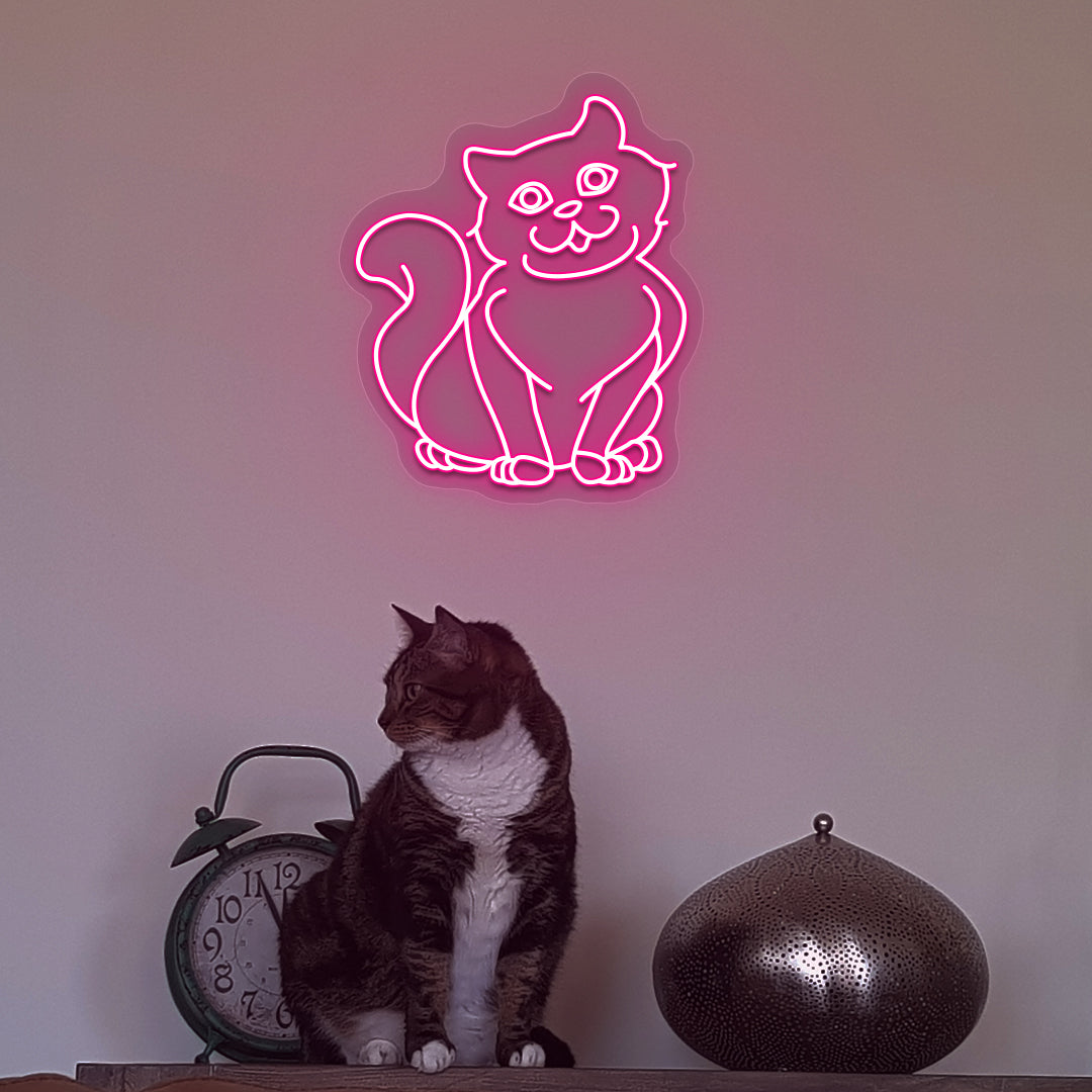 Wall decor with a pink LED cat neon sign glowing on the wall and a cute cat below.